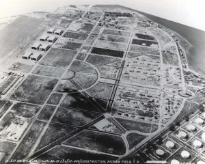 The water tower, paved roads, underground power, family housing, Bishop Point dock, hangars, Base Operations, apron and taxiway are in place, November 17, 1938. The railroad has been moved to Hangar Avenue and men continue to live in tents.  