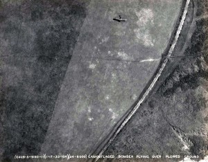 U.S. Army Air Corps camouflaged bomber flying over plowed ground, January 17, 1933.   