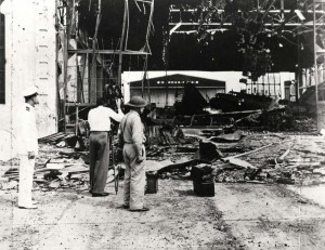 Inspecting Hickam Field Hangar 1 damage, December 7, 1941. A 5th Bombardment Group B-18 aircraft can be seen in background at right.   