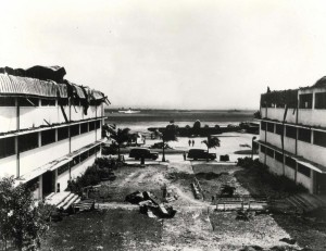Looking out toward Hangar Avenue and the flight line from coutyard between heavily damaged Wing E and Wing D of the big barracks at Hickam Field, December 7, 1941. 