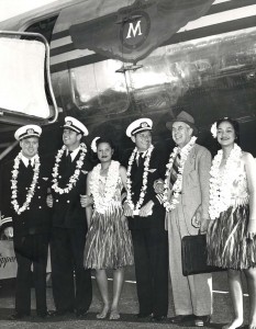 Pilots being welcomed with leis in front of an aircraft