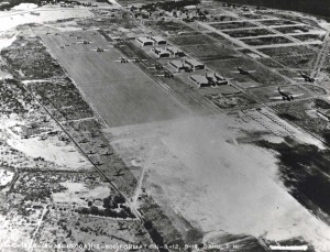 A formation of Martin B-12 and Douglas B-18 bombers over Hickam Field with some roads paved. The Diamond Head extension of the taxiway was begun by grading equipment and the railroad is in place to the left of the taxiway, June 18, 1938. 