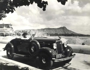 1935 Chevrolet convertible with Diamond Head and Waikiki Beach in the background.   
