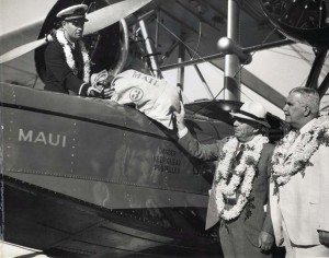 Inter-Island Airways October 8, 1934. Governor Joseph B. Poindexter hands the first air mail to co-pilot James Hogg for interisland delivery. Postmaster Charles Chillingworth looks on