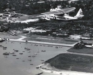 Inter-Island Airways. Sixteen person U.S. air mail plane flies above newly developed federal yacht harbor in Honolulu.