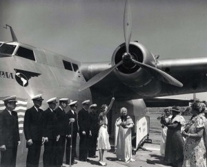 Helen Poindexter christens the Pan American Honolulu Clipper with coconut milk, dipping the fluid from a shell held by a member of the one-time royal court, then casting it to the four winds before touching the plane. 1939.  