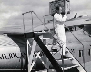 J A Brooks, PAA employee, carries first RCA Victor radio set from Pan American Clipper.