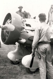 P-26 from Wheeler had a flash fire on start up at Morse Field, Hawaii. Squadron commander surveys damage. Pilot is wearing a Mae West. Someone had to stand on left wing and crank the engine with a hand crank to get it started, 1941. 