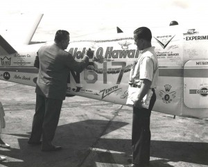 Col. Cholermahai Charuvastr, left, the Tourist Organization of Thailand's Director General, signs his name on the Bonanza fuselage while Captain Banfe looks on. 